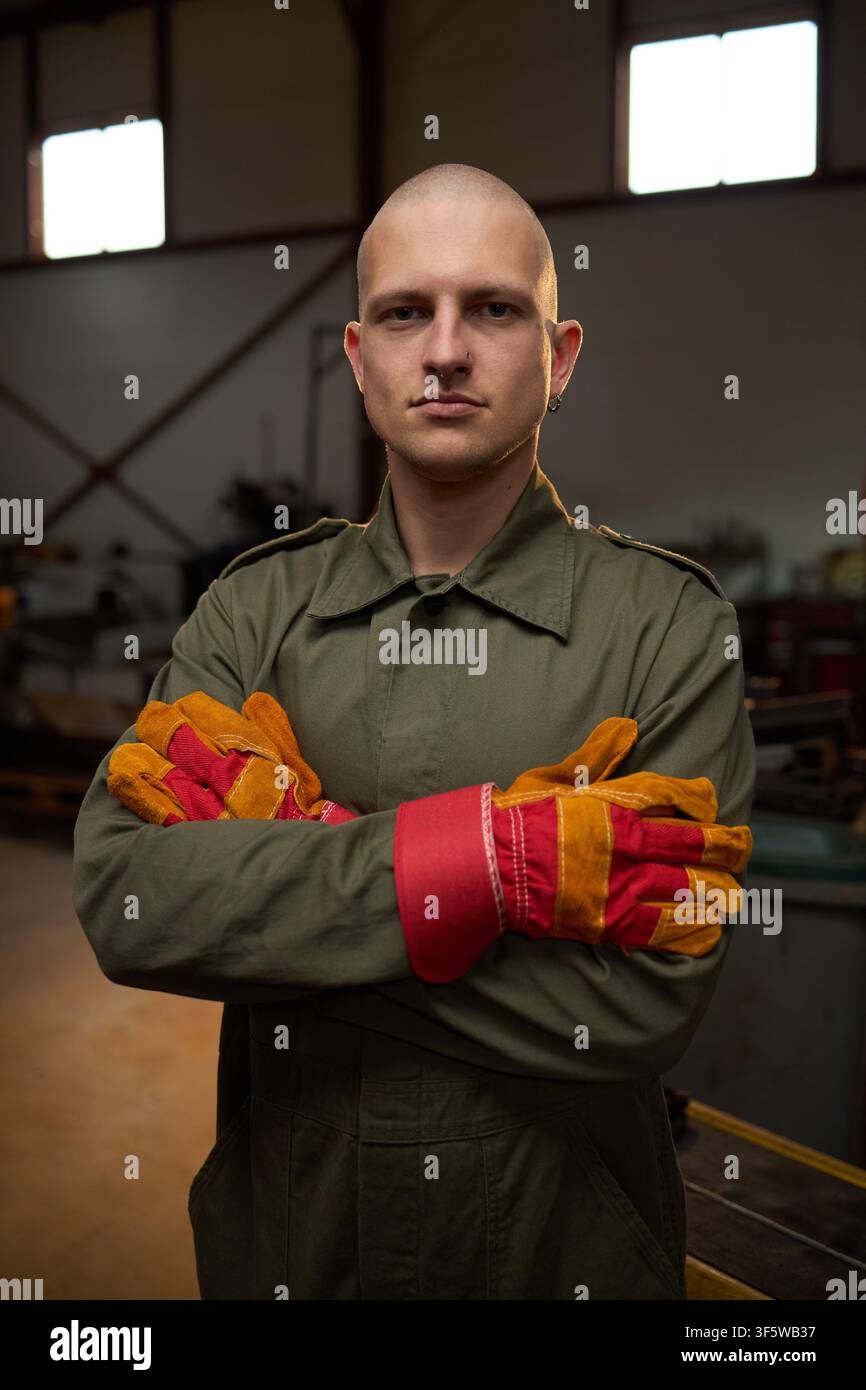 Porträt eines männlichen Schweißers, der mit verschränkten Armen in der Werkstatt steht Stockfoto