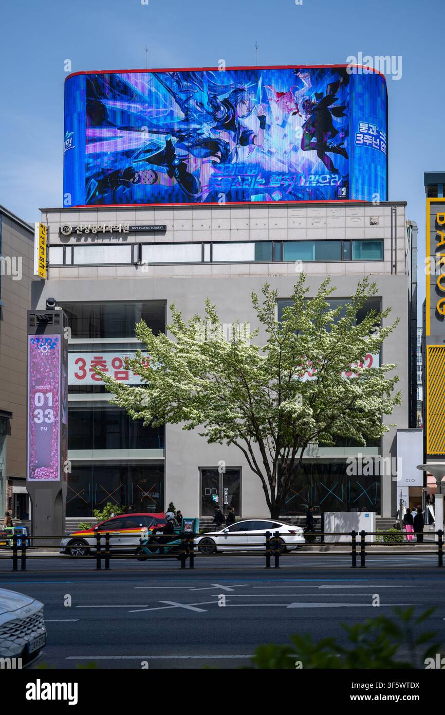 Ein Geschäftsgebäude mit einem großen LED-Werbebildschirm auf dem Dach auf einer Straße in Gangnam, Seoul. Stockfoto
