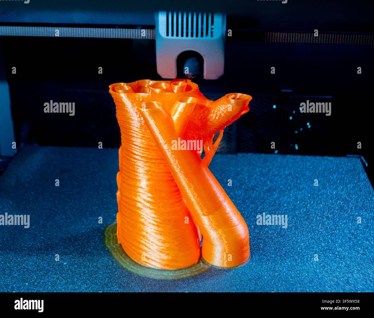 Prozessdruck auf 3D-Drucker. Der 3D-Druckprozess aus geschmolzenem orangefarbenem Kunststoff. 3D-Drucktechnologie. FDM-Technologien. Fused Deposition Modeling. Additives Fertigungsverfahren. Stockfoto