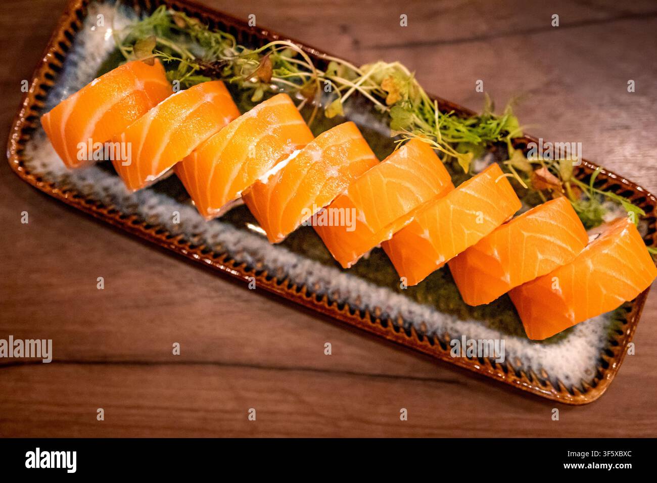 Elegante Anordnung von Philadelphia-Sushi-Rollen mit Mikrogrün-Garnitur. Japanisches Sushi-Konzept für Restaurantessen und asiatische Esskultur. Stockfoto