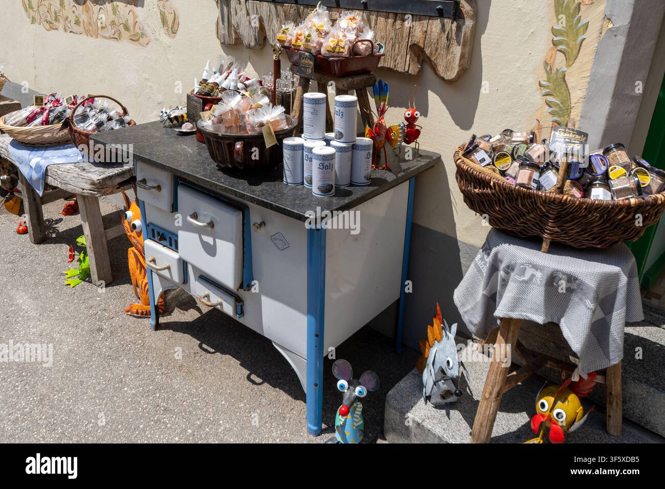 Outdoor-Souvenir-Ausstellung von lokalem Salz und Gewürzen auf einem alten Vintage-Herd mit kleinen Metallfiguren. Hallstatt, Österreich - 22. Juni 2026 Stockfoto