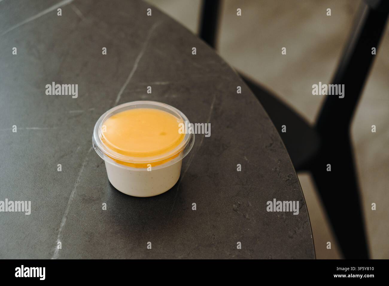 Vanille-Panna-Cotta mit glatter Mangosauce serviert in einem To-go-Becher. Klare minimalistische Komposition mit Kopierraum. Stockfoto