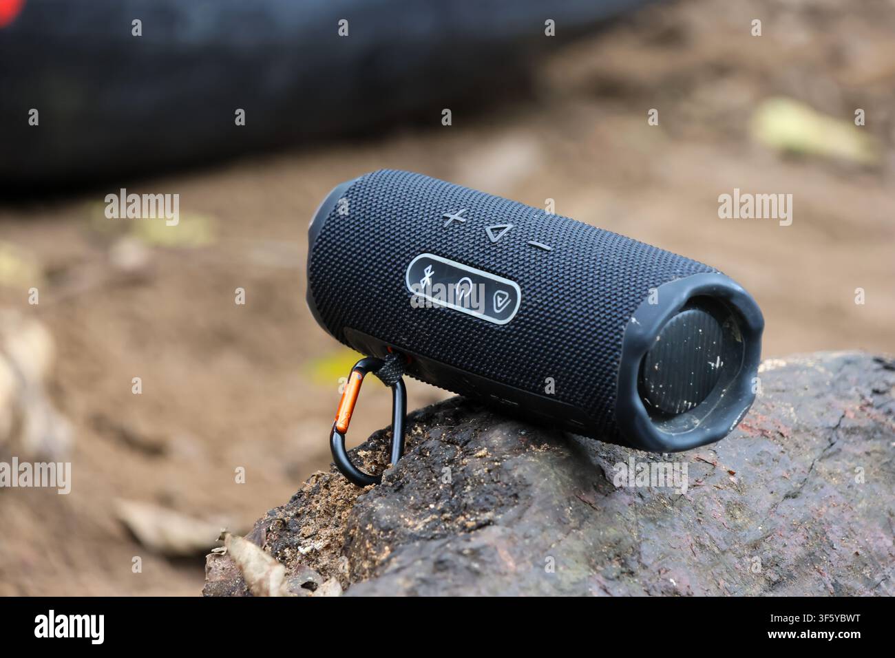 Ein tragbarer Bluetooth-Lautsprecher mit strukturiertem Stoffgehäuse und Karabiner für Outdoor-Lifestyle mit lächelndem Klang Stockfoto