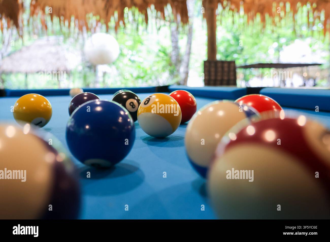 Ein lebendiger Poolball-Nahaufnahme blauer Tisch gelbe Acht-Ball rote Spielkugel Freizeitsport tropischer Hintergrund Stockfoto
