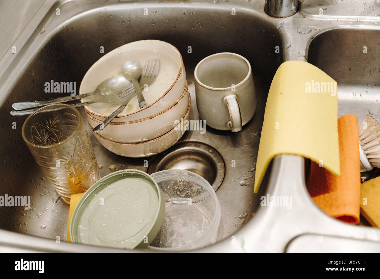 Benutztes Geschirr, Gläser und Besteck, die vor dem Spülen in einem Küchenwaschbecken gestapelt sind. Alltägliche Reinigungsroutine in einer Café- oder Restaurantküche. Stockfoto
