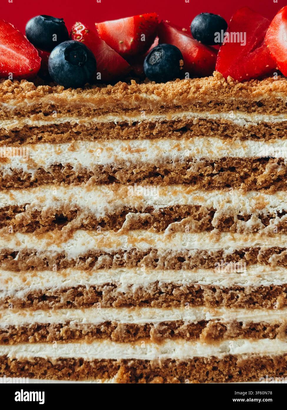 Klassischer geschichteter Honigkuchen Medovik, dekoriert mit frischen Erdbeeren und Blaubeeren - Smartphone-aufgenommenes Stockfoto