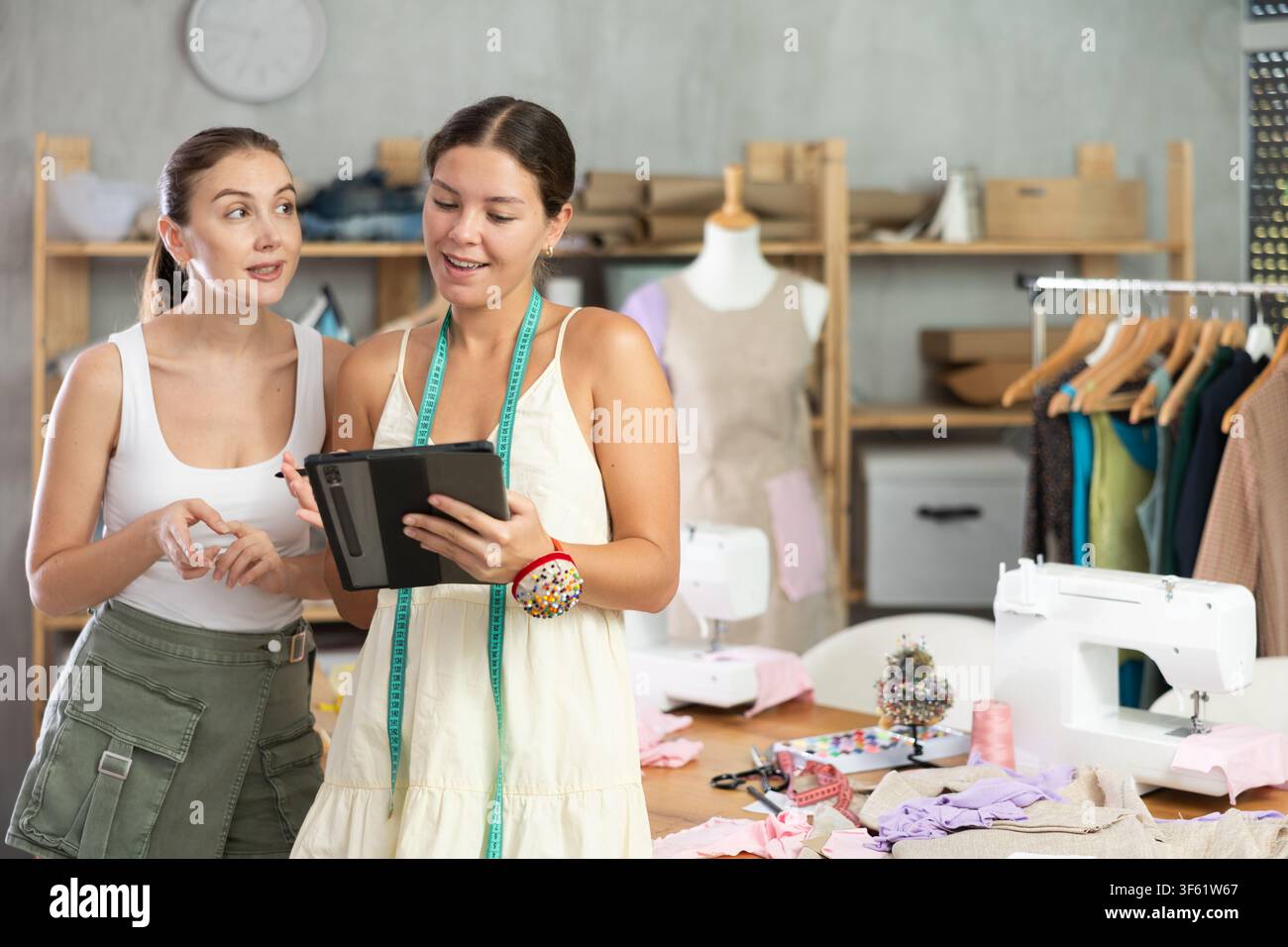 Zwei Schneiderinnen zeichnen ein Modell von Kleidung auf einem Tablet Stockfoto