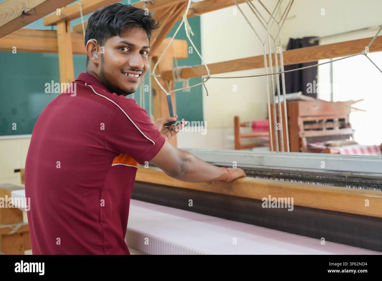 Lächelnder indischer Weber oder Arbeiter, der traditionelles Gewebe auf einem hölzernen Handwebstuhl herstellt, Beschäftigung und Arbeit, Skill India Stockfoto