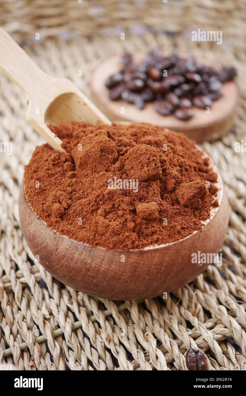 Kaffeepulver in einer Holzschale und geröstete Bohnen Stockfoto