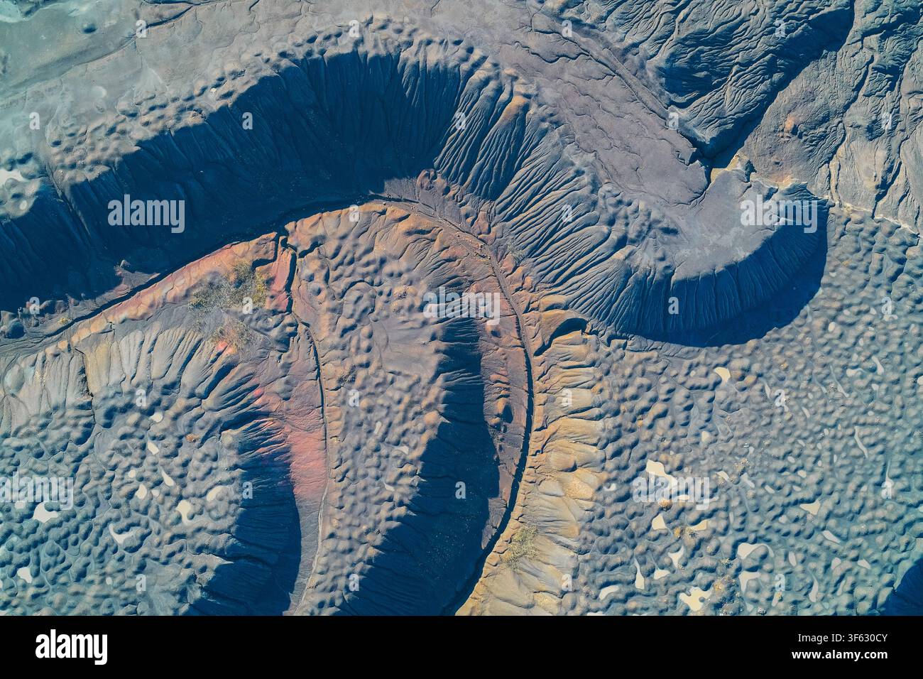 Erosierte gebogene Grate eines industriellen Schlackenhalden-Abfallhaufens mit texturierter grauer Erde und Mineralablagerungen. Hochwinkelaufnahme, die Landverschlechterung, Umweltschäden, Grubenreste und Ödlandtopographie einfängt. Stockfoto