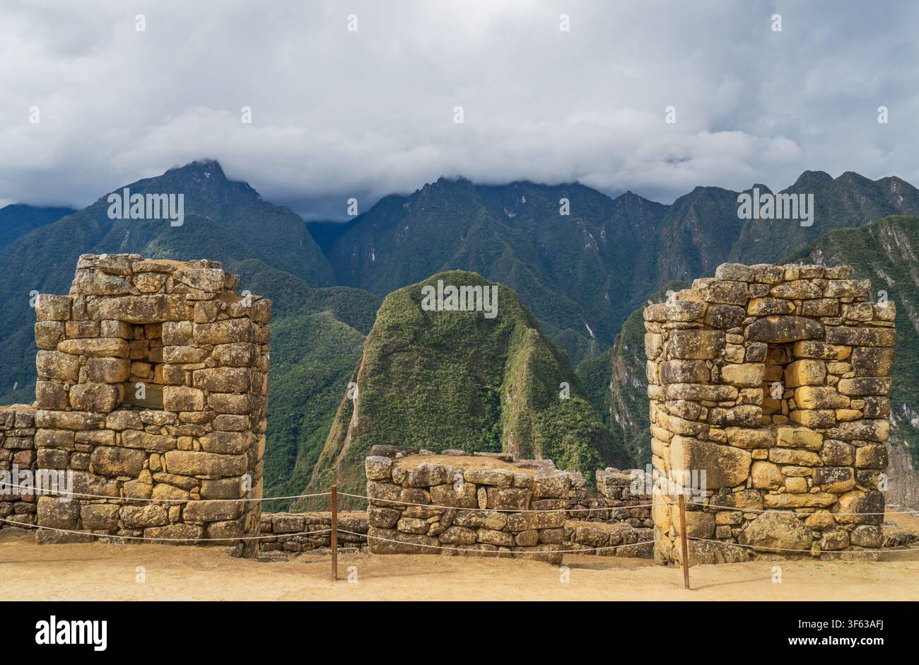 Alte Inka-Steinhäuser und Wohnruinen in Machu Picchu, die die grünen Gipfel und tiefen Wolken der Anden in Peru einrahmen Stockfoto