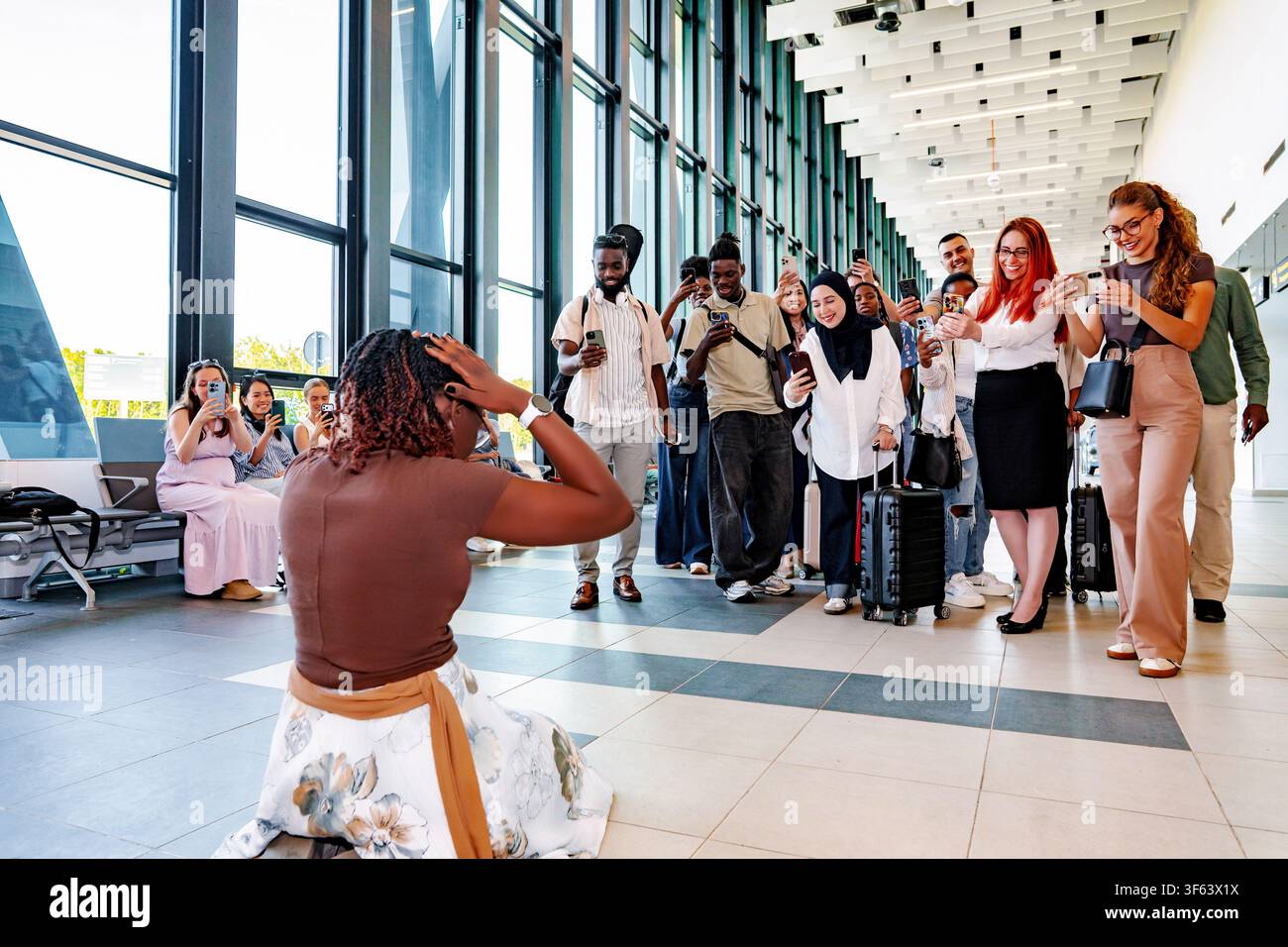 Frau, die sich von Menschen überwältigt fühlt, die sie mit Smartphones im Flughafen filmen Stockfoto