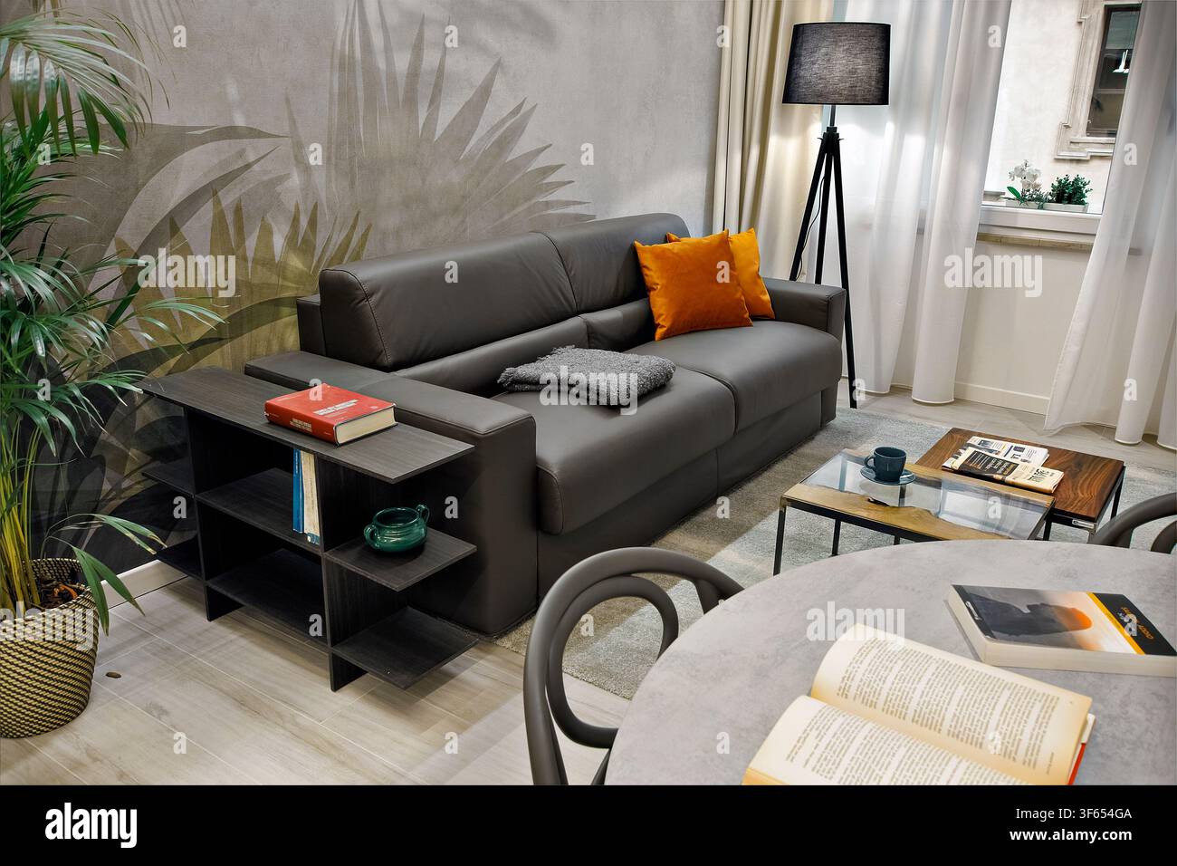 Zeitgenössische Wohnung in Turin, Italien, umgebaut von Büro zu Wohnzwecken, mit Ledersofa, Blumentapete, Esstisch und Fenster Stockfoto
