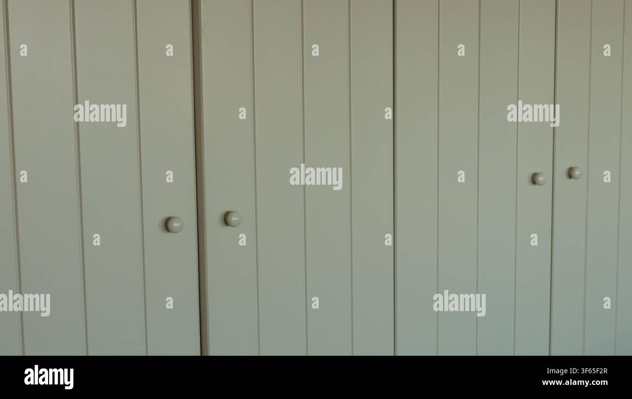 Cremige Schrank-türen mit Nut-und-Feder-Verzierung und runden Holzknöpfen — Einbau-Speicher, Cottage-Innenarchitektur-Detail und neutrales Hintergrundkonzept Stockfoto
