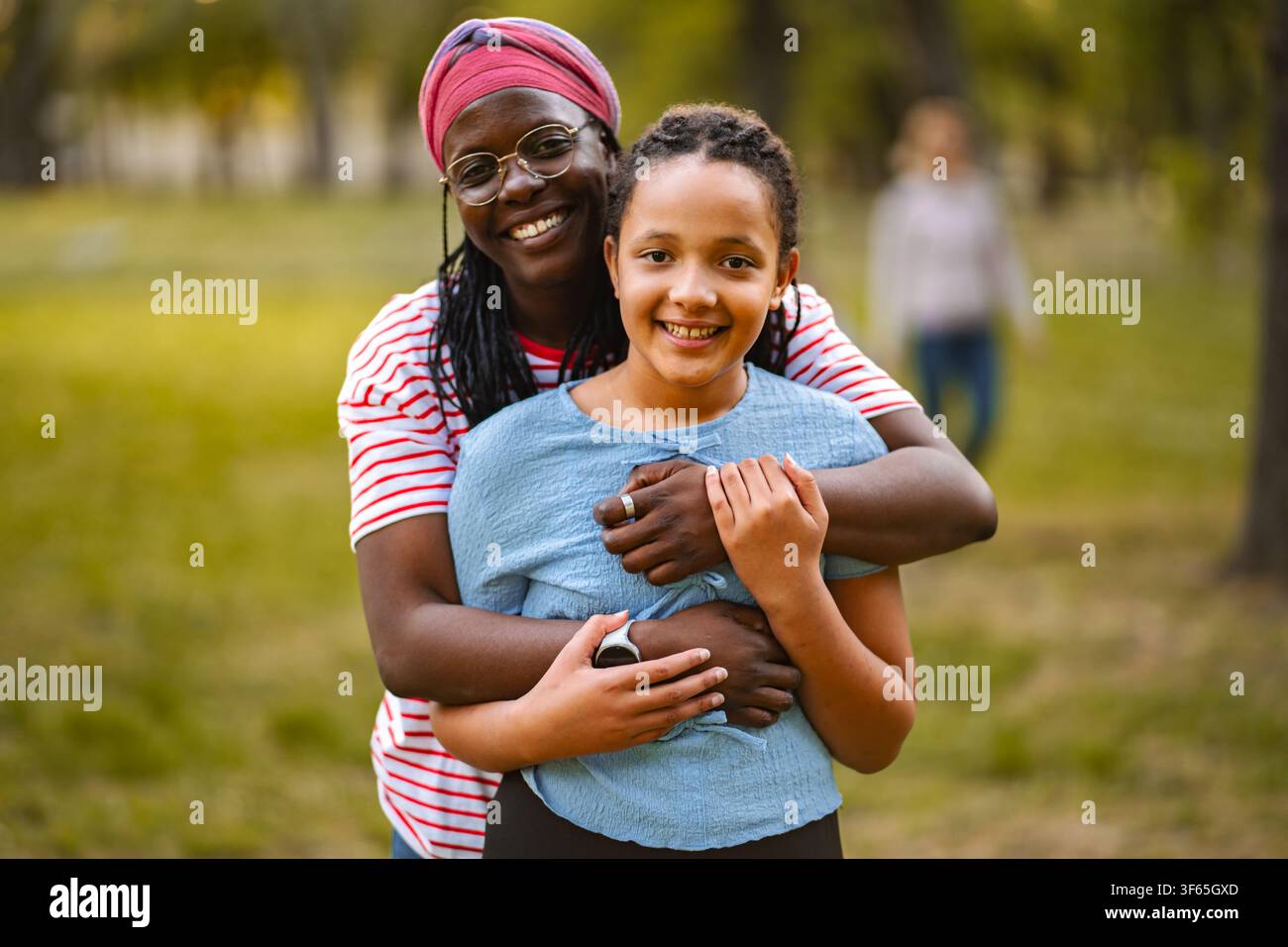 Zufriedene Mutter umarmt verschiedene Tochter im Park Stockfoto
