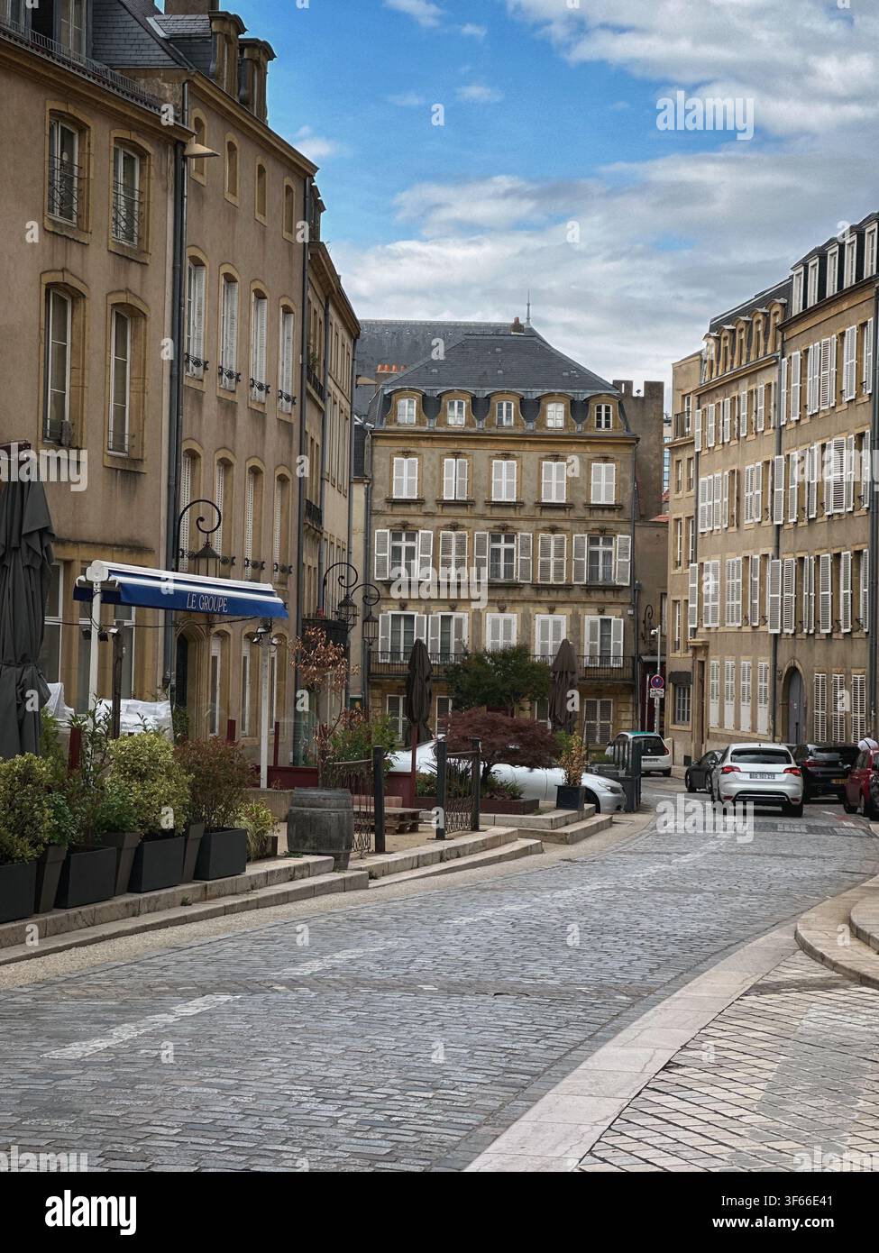 Bezaubernde Kopfsteinpflasterstraße in einer historischen europäischen Stadt. Idyllischer Blick auf eine schmale Kopfsteinpflasterstraße, gesäumt von klassischen Gebäuden im klassischen Stil, Shuttles - Smartphone-aufgenommenes Stockfoto
