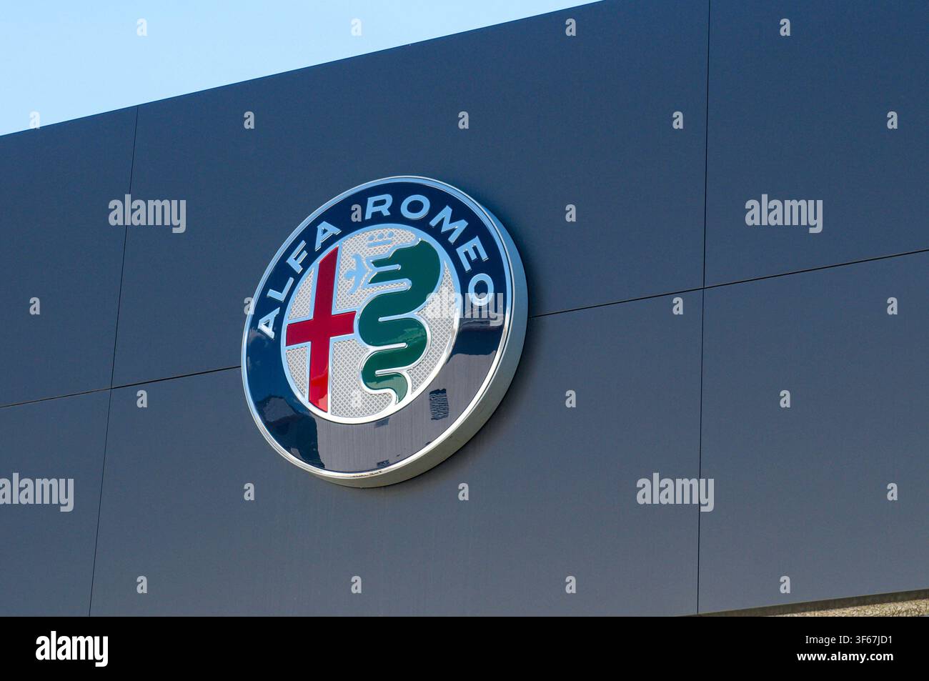 Cadenazzo, Ticino, Schweiz - 3. Juli 2026: Alfa Romeo-Firmenlogo-Schild, das an der dunkelgrauen Außenfassade eines offiziellen Autohandels montiert ist Stockfoto