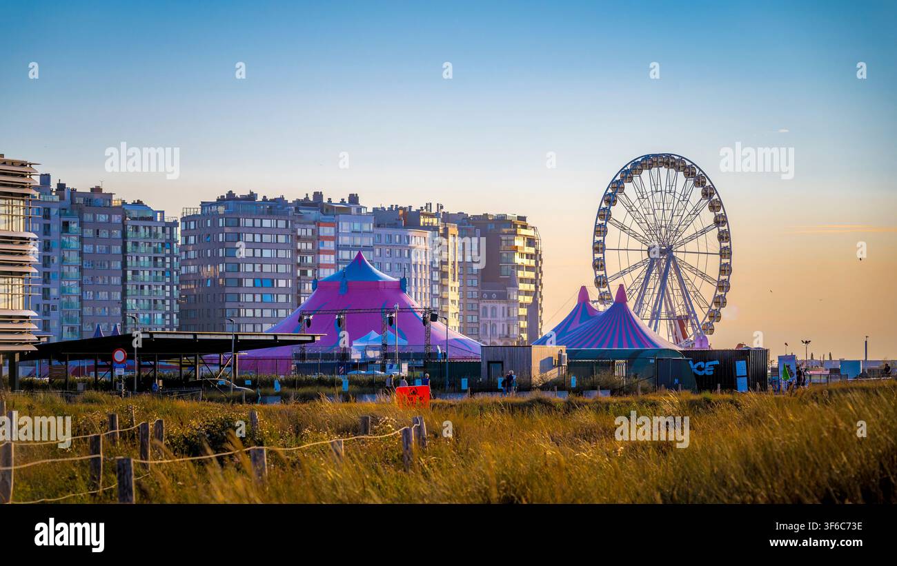 Ostend, Belgien, 4. August 2026: Riesenrad und farbenfrohe Veranstaltungszelte an der Küste von Ostend, Belgien, mit modernen Wohnhäusern im Hintergrund Stockfoto