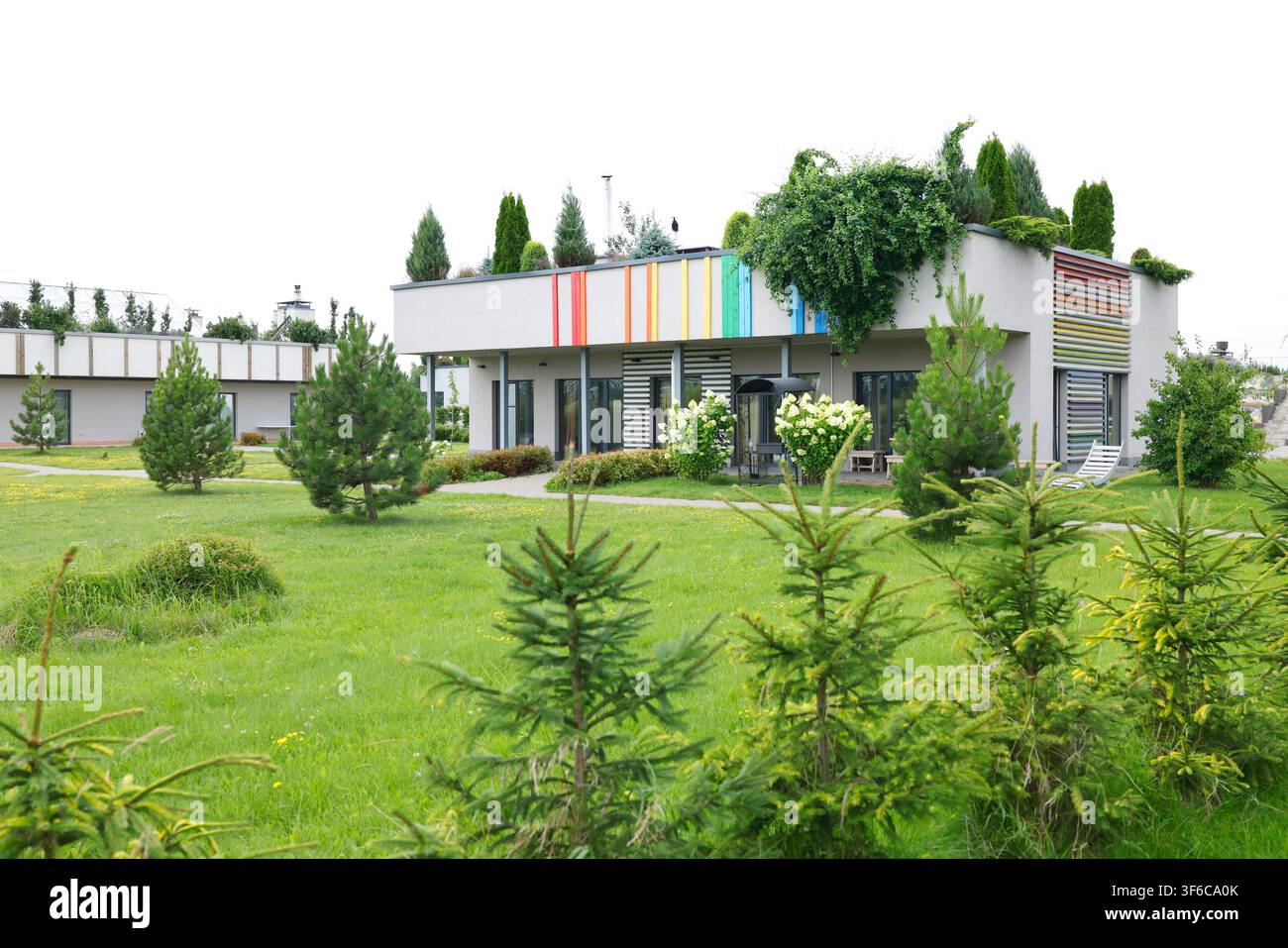 Modernes umweltfreundliches Hausdesign mit grüner Dachgarten. Nachhaltiges Architekturkonzept, das minimalistisches Wohnen zeigt. Innovative Wohnbebauung Stockfoto