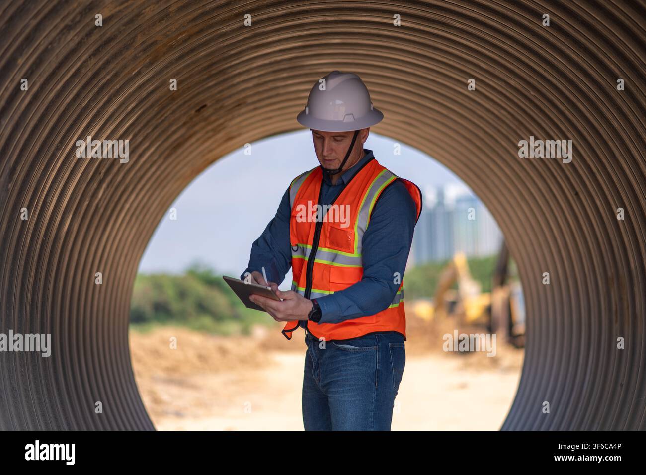 Bauleiter oder Ingenieur arbeitet auf einer Rohrbaustelle zur Inspektion von Baudetails mit schweren Maschinen Stockfoto