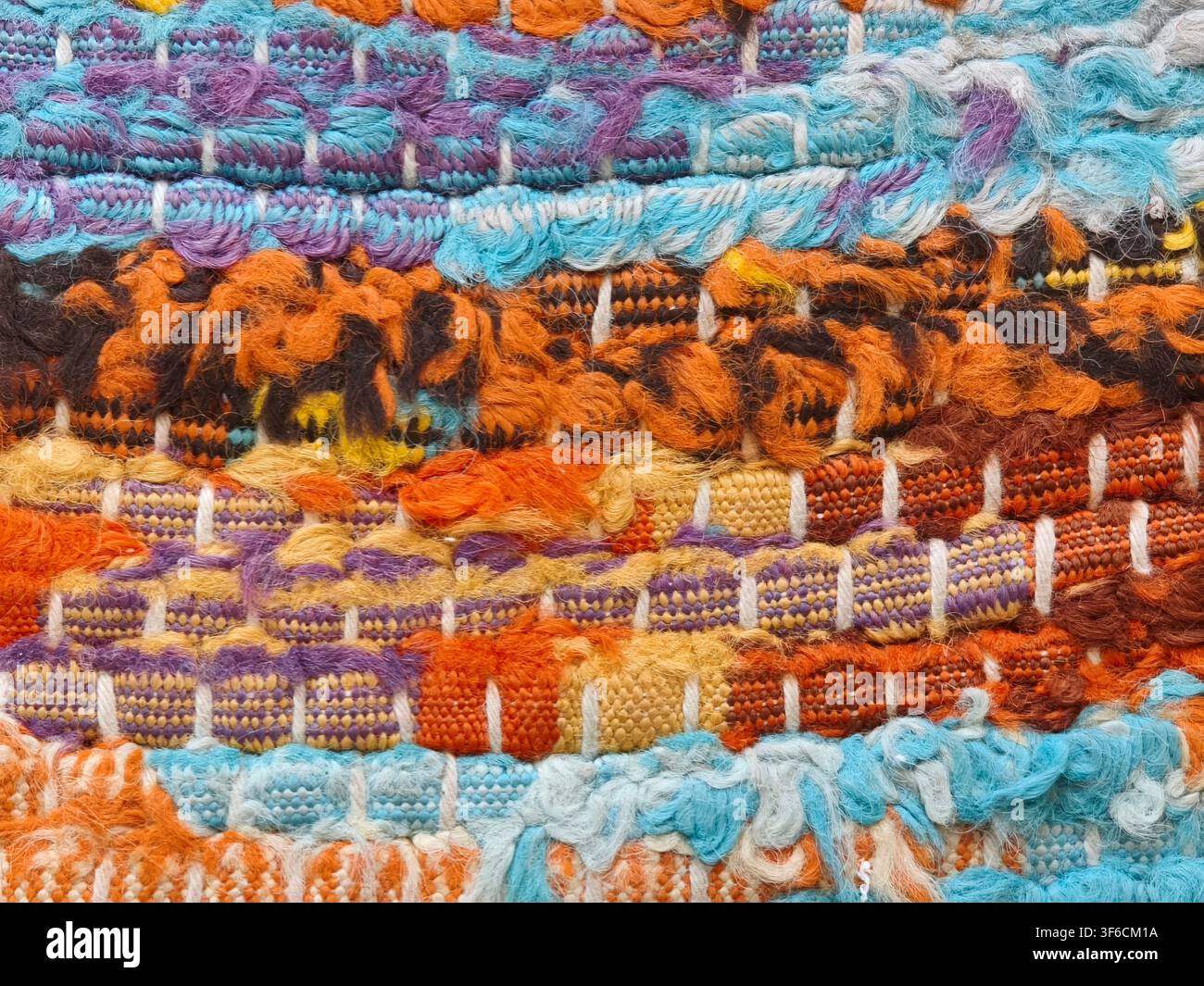Bunte gewebte Lumpen-Teppichtextur mit orangefarbenen, blauen und violetten Stoffgarnen Stockfoto