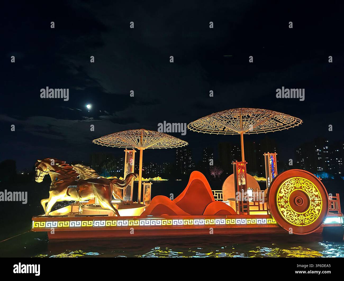 Ansicht der beleuchteten Xianyang Ancient Ferry Bridge-Installation mit einer goldenen Pferdeskulptur und dekorativen Regenschirmen, die auf dem Fluss schwimmen a Stockfoto