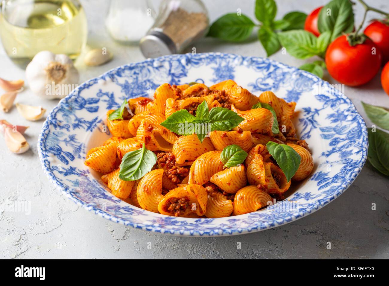 Köstliche Pipe Rigate Pasta mit Bolognese-Fleischsauce und frischen Basilikumblättern Stockfoto