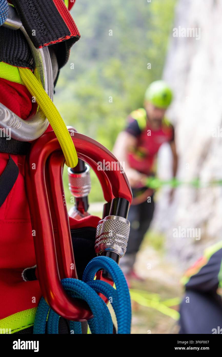 Nahaufnahme von verriegelnden Karabinern an einem Klettergurt mit verschwommenem Kletterer im Hintergrund Stockfoto