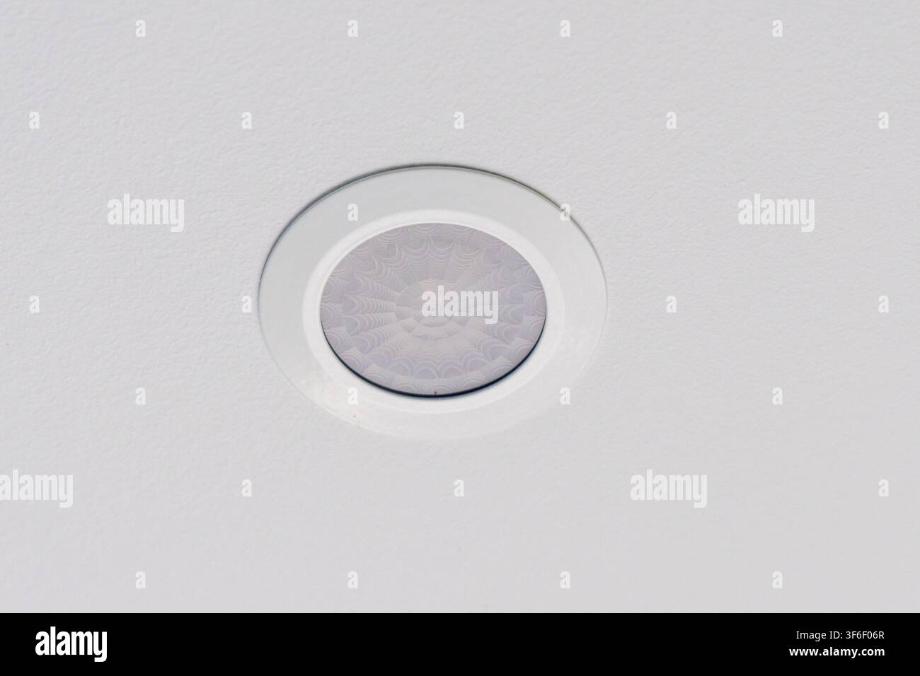 Eine moderne Einbauleuchte ist an einer strukturierten weißen Decke installiert und spendet sanftes und diffuses Licht im Raum Stockfoto