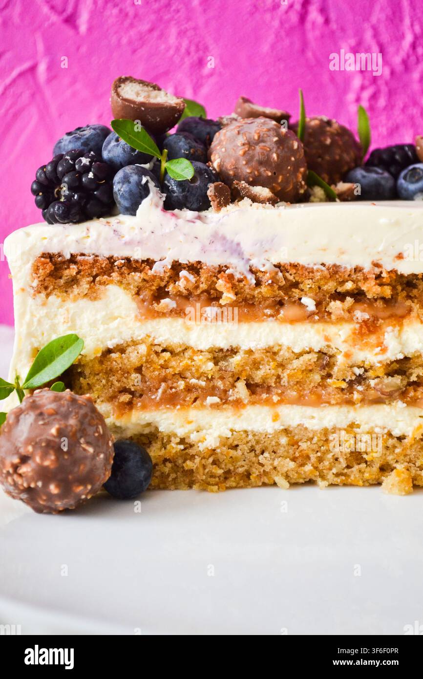 Scheibe Karottenkuchen mit Karamellschicht und Frischkäse, dekoriert mit Blaubeeren, Brombeeren und Schokoladentrüffeln Stockfoto