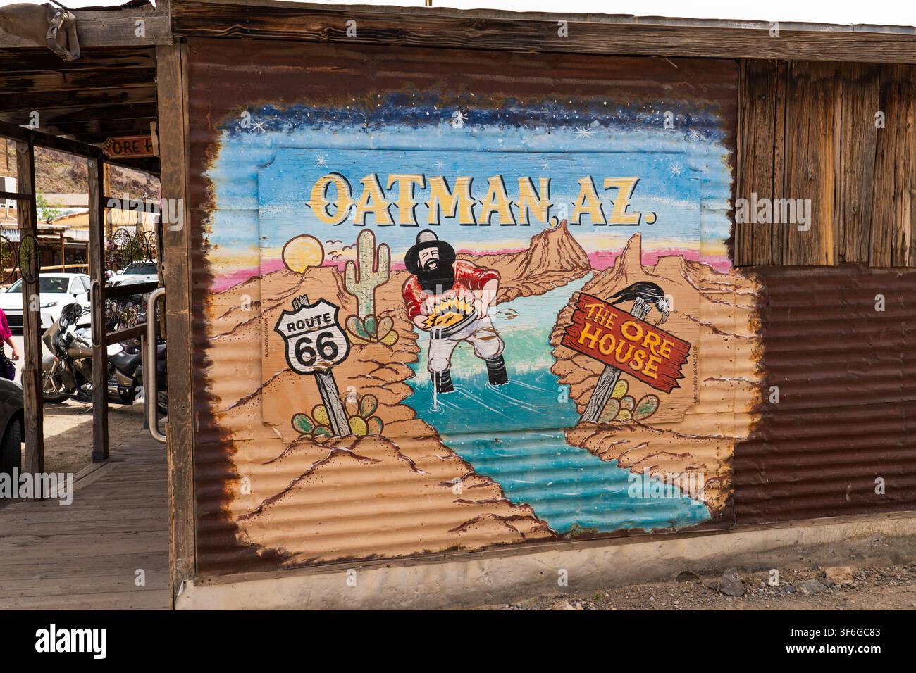 Handgemalte farbenfrohe Wüstenwandmalerei mit Route-66-Schild und Goldsucher-Charakter auf einer rustikalen Wellblechwand in Oatman, Arizona Stockfoto