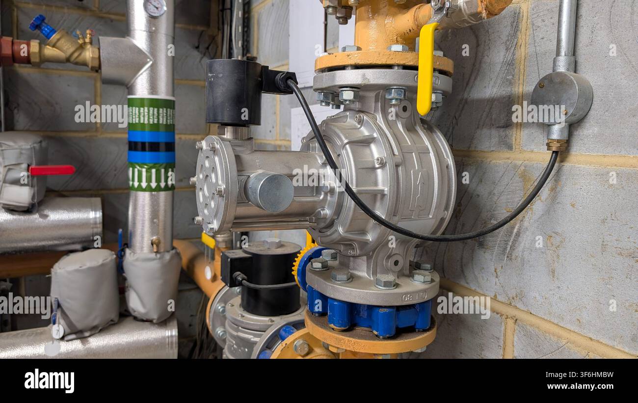 Industrielles Gas-Solenoid-Absperrventil, das in einem Gebäudeversorgungsraum an kommerziellen Rohrleitungen installiert ist. Stockfoto