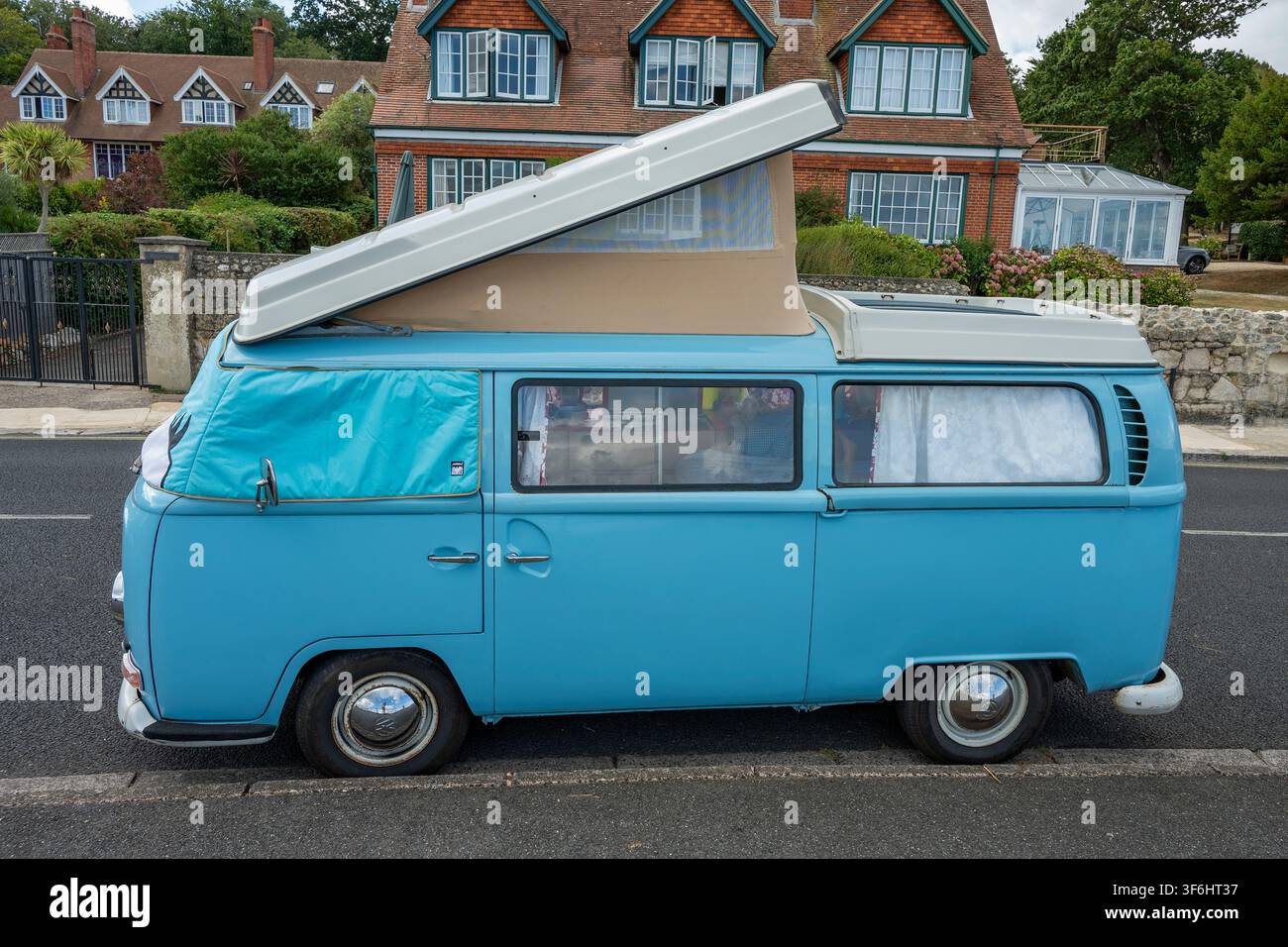 Klassischer VW Volkswagen T2 Campingbus mit Schiebefenster, geparkt am Straßenrand mit auffahrendem Dach und Fensterrollos. Stockfoto