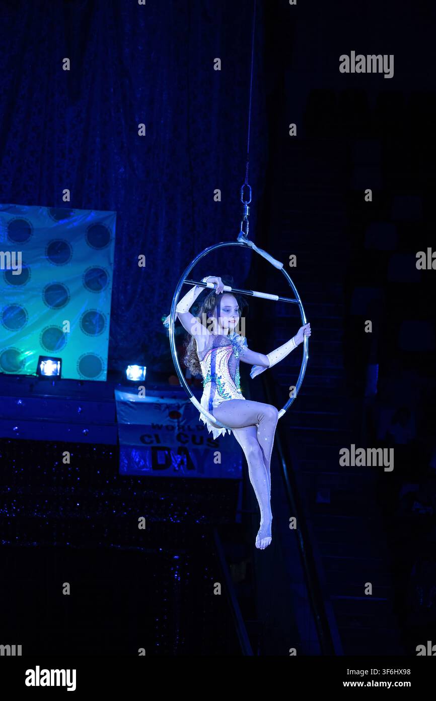 Mädchen führt eine Luftreifen-Akrobatik im Zirkus aus. Konzept: Veranstaltungen zum Welttag des Zirkus, künstlerische Jugendsportgymnastik, Bühnenunterhaltung. Stockfoto