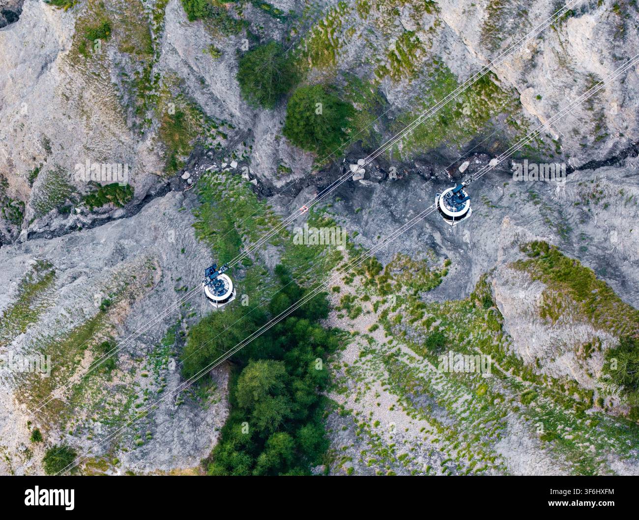 Luftaufnahme von Seilbahnen, die das raue alpinen Gelände des Mont-Blanc-Massivs mit felsigen Hängen, grüner Vegetation und Bergspalten in Cour durchqueren Stockfoto