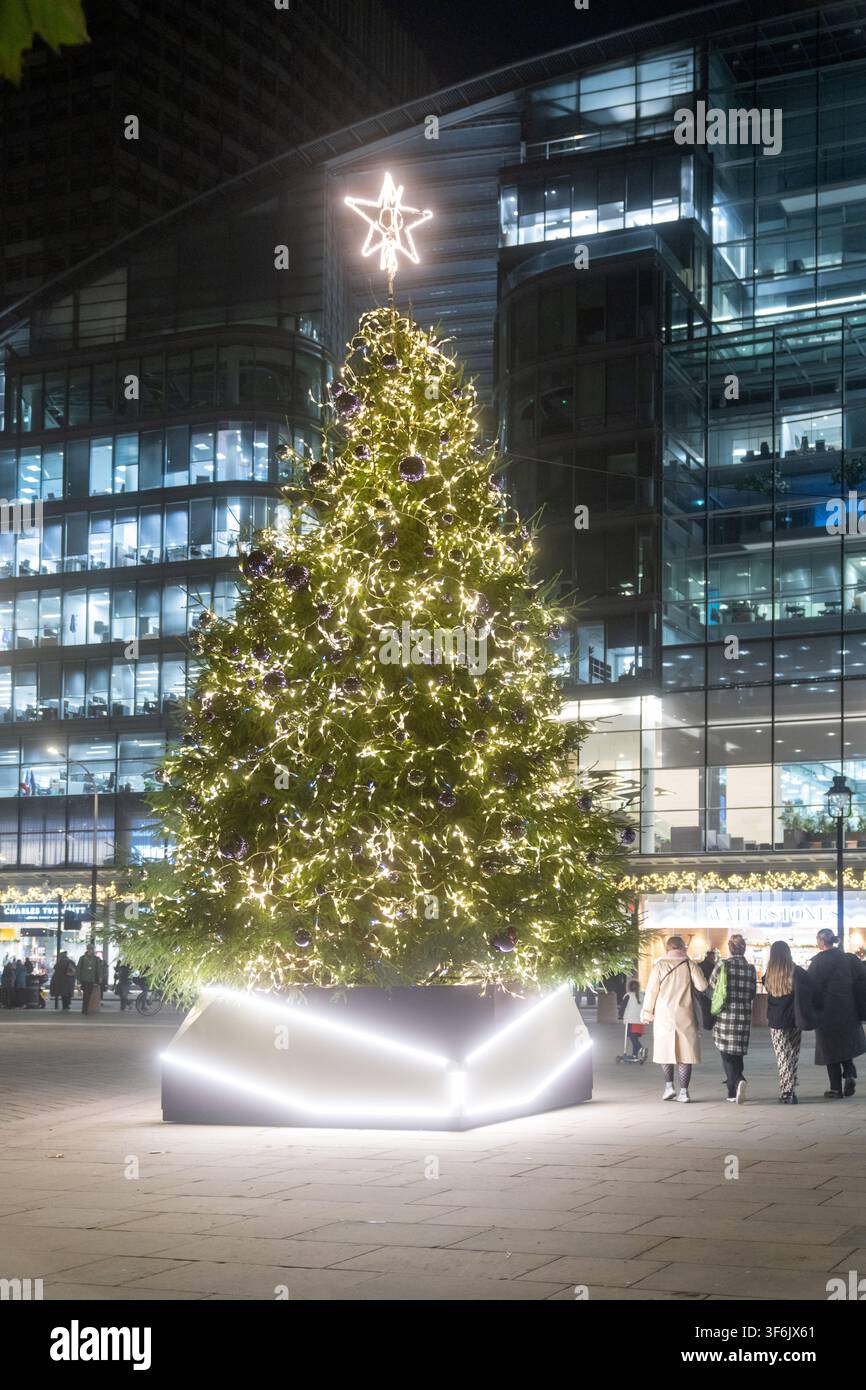 Passanten genießen den festlichen Weihnachtsbaum am Cardinal Place in Victoria, London, der die Ankunft der Feiertagssaison markiert. Stockfoto