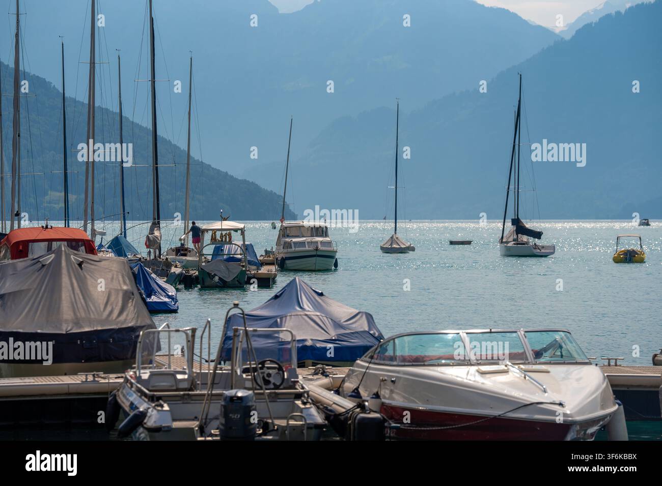 Spiez, Schweiz – 28. Juni 2026: Idyllischer Augenhöhe-Blick auf Boote und Yachten, die im Hafen von Spiez entlang des funkelnden türkisfarbenen Thuner Sees liegen. Sanftes Tageslicht Stockfoto