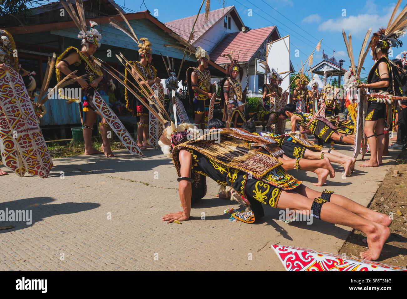 Samarinda, Indonesien - 25. Juni 2026. Eine Gruppe junger Dayak Kenyah-Krieger in vollständiger traditioneller Zeremonienkleidung, die Liegestütze auf dem Boden ausführen. Stockfoto