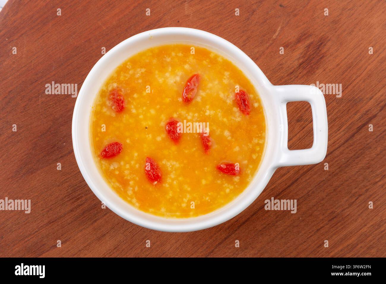 Goldener Hirse-Kürbisbrei garniert mit getrockneten Goji-Beeren Stockfoto