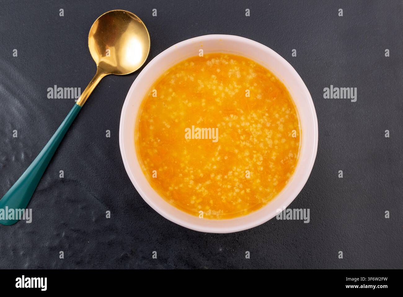 Goldener Hirse-Kürbisbrei garniert mit getrockneten Goji-Beeren Stockfoto