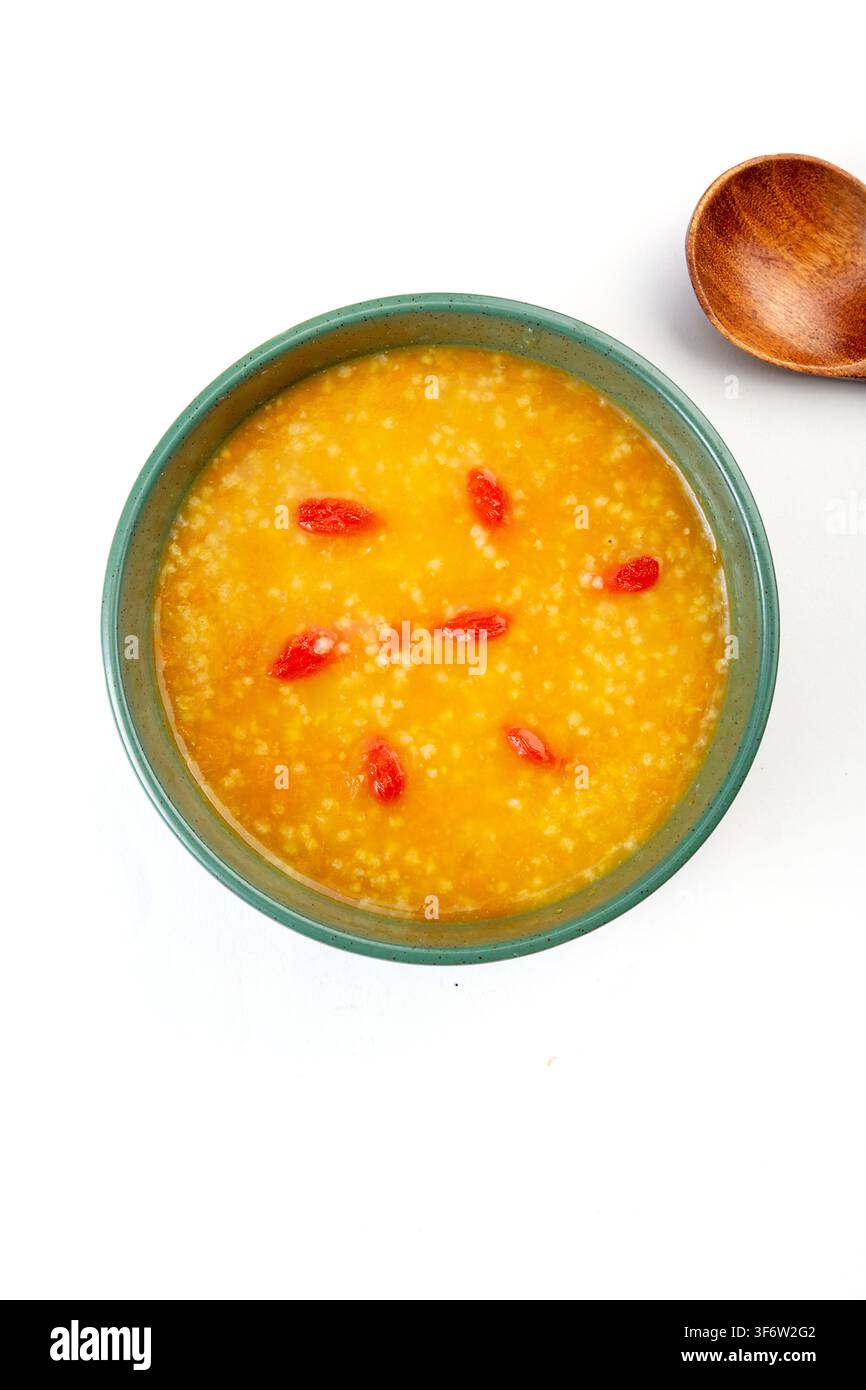 Goldener Hirse-Kürbisbrei garniert mit getrockneten Goji-Beeren Stockfoto