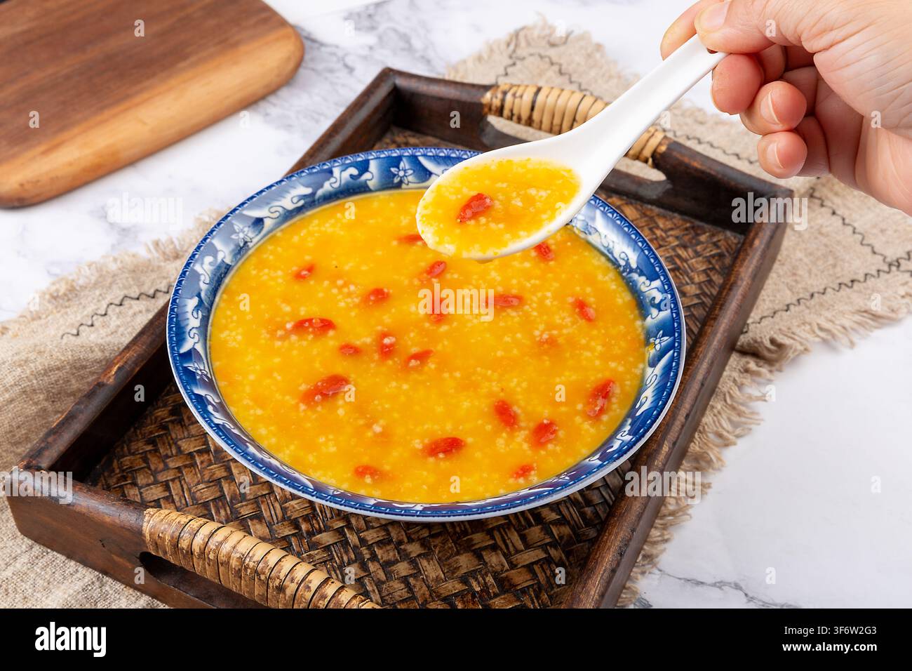 Goldener Hirse-Kürbisbrei garniert mit getrockneten Goji-Beeren Stockfoto