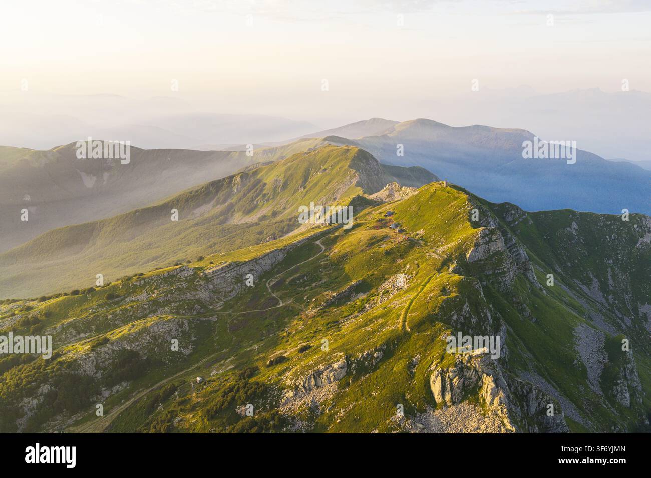 Luftbild der üppigen grünen Bergrücken und felsigen Gipfel des Tosko-Emilianischen Apennins zur goldenen Stunde in Cerreto Laghi, Emilia-Romagna, Italien. Stockfoto