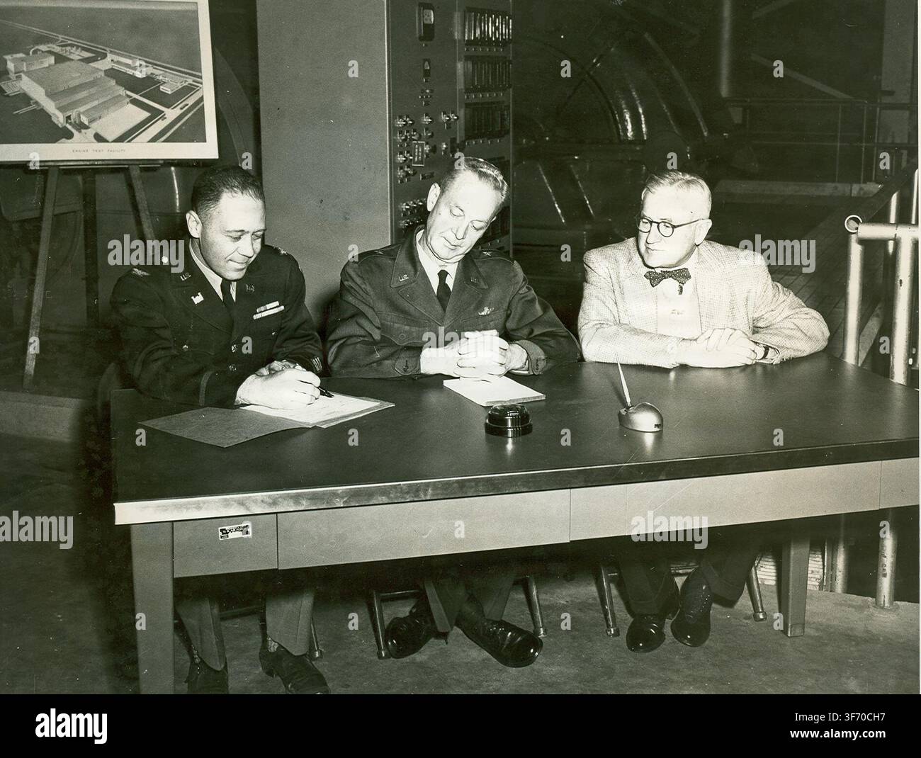 Oberst L.E. Cox, ein Ingenieur des U.S. Army Corps of Engineers, bereitet die Übergabe des Arnold Engineering Development Center Engine Test Facility Exhaust Compressor Building an Brigadegeneral Samuel Harris, damals AEDC-Kommandant, vor, während einer Zeremonie am 30. November 1953 im Zentrum, wobei Thomas Farrell, Geschäftsführer der Arnold Research Organization, ebenfalls anwesend war. Stockfoto