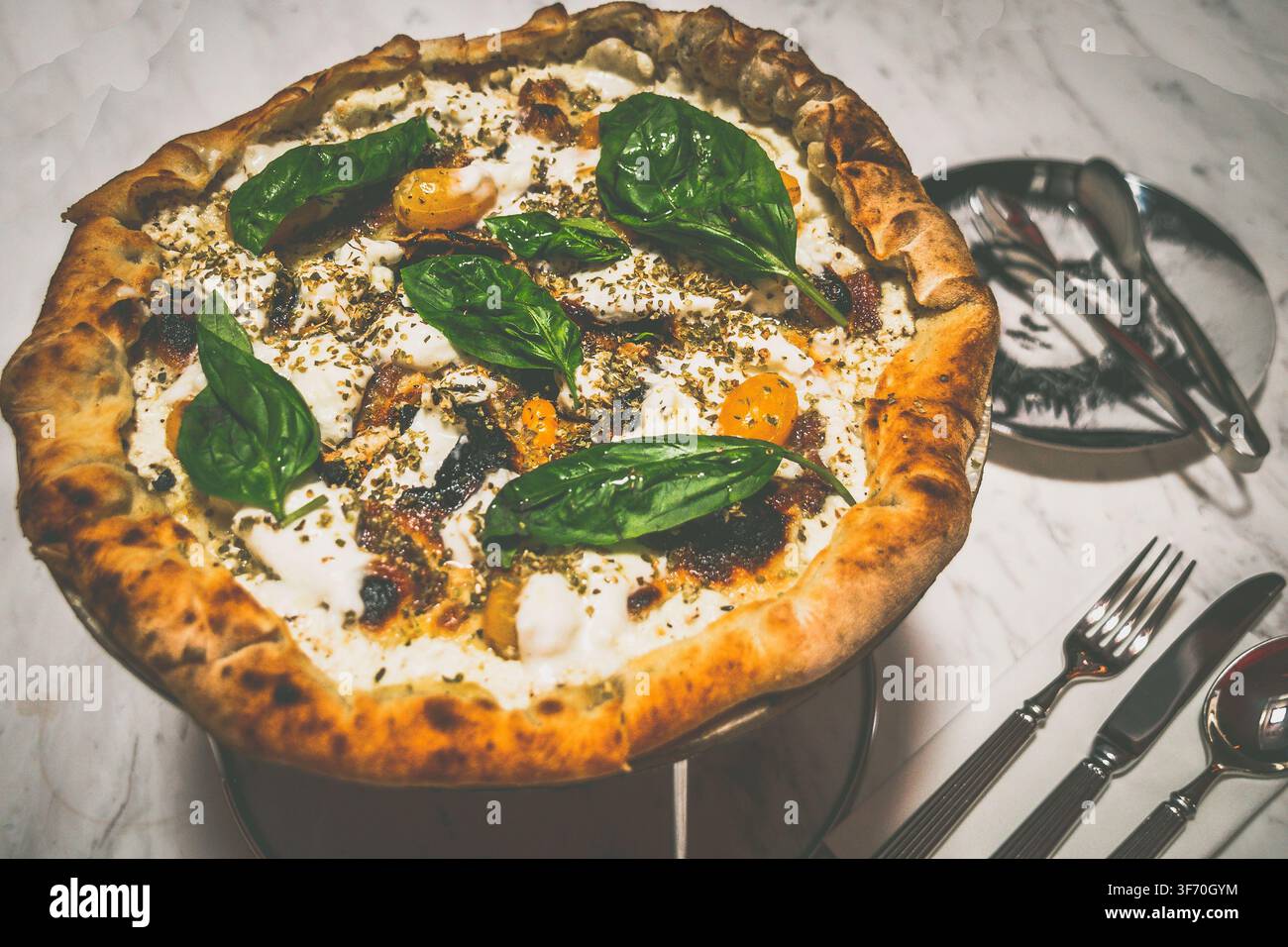 Pizzakruste gefüllt mit Ricotta-Käse und schwarzem Pfeffer, Anchovis, frischem Burrata-Käse, Oregano, Tomate Spacchetelle Yellow, Basilikum, extra nativem Öl Stockfoto