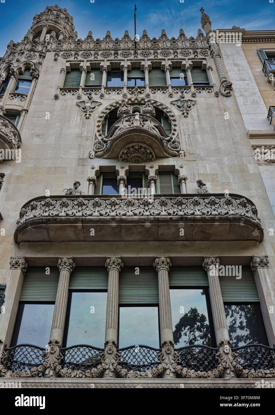 Verschnörkelte modernistische Fassade mit aufwendigen Steinmetzarbeiten und schmiedeeisernen Balkonen in Barcelona, Spanien Stockfoto