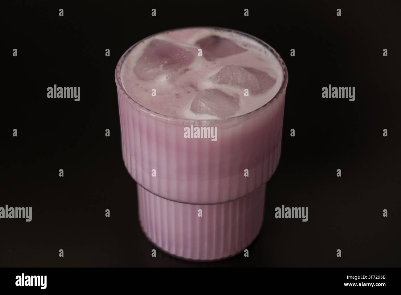 Rosa Eismatcha-Getränk mit Eiswürfeln auf schwarzem Hintergrund Stockfoto