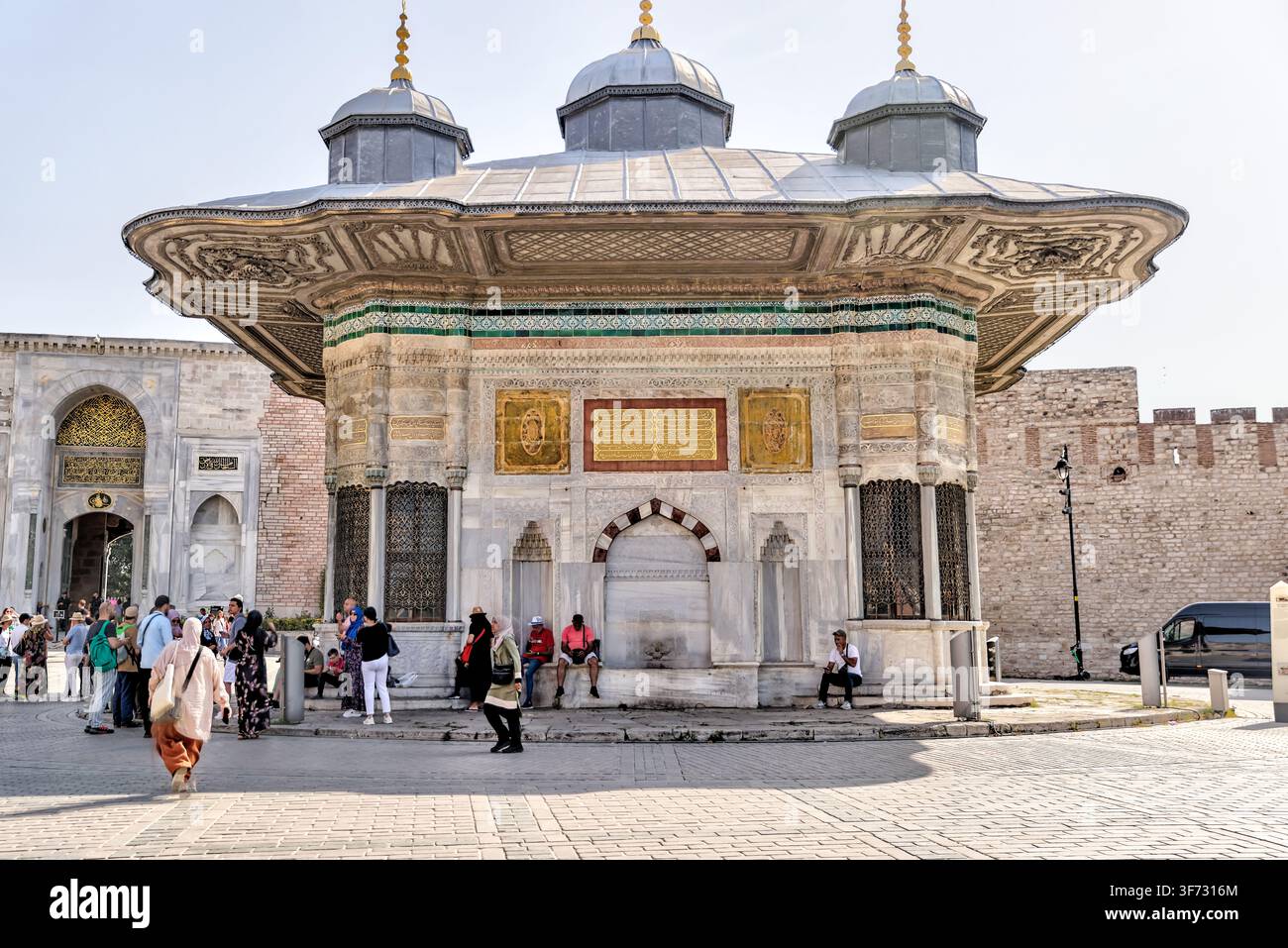 Touristen besuchen die Fontaine des Sultans Ahmed III. (III. Ahmed Çeşmesi) neben dem Kaiserlichen Tor des Topkapı-Palastes in Istanbul, Türkiye. Stockfoto