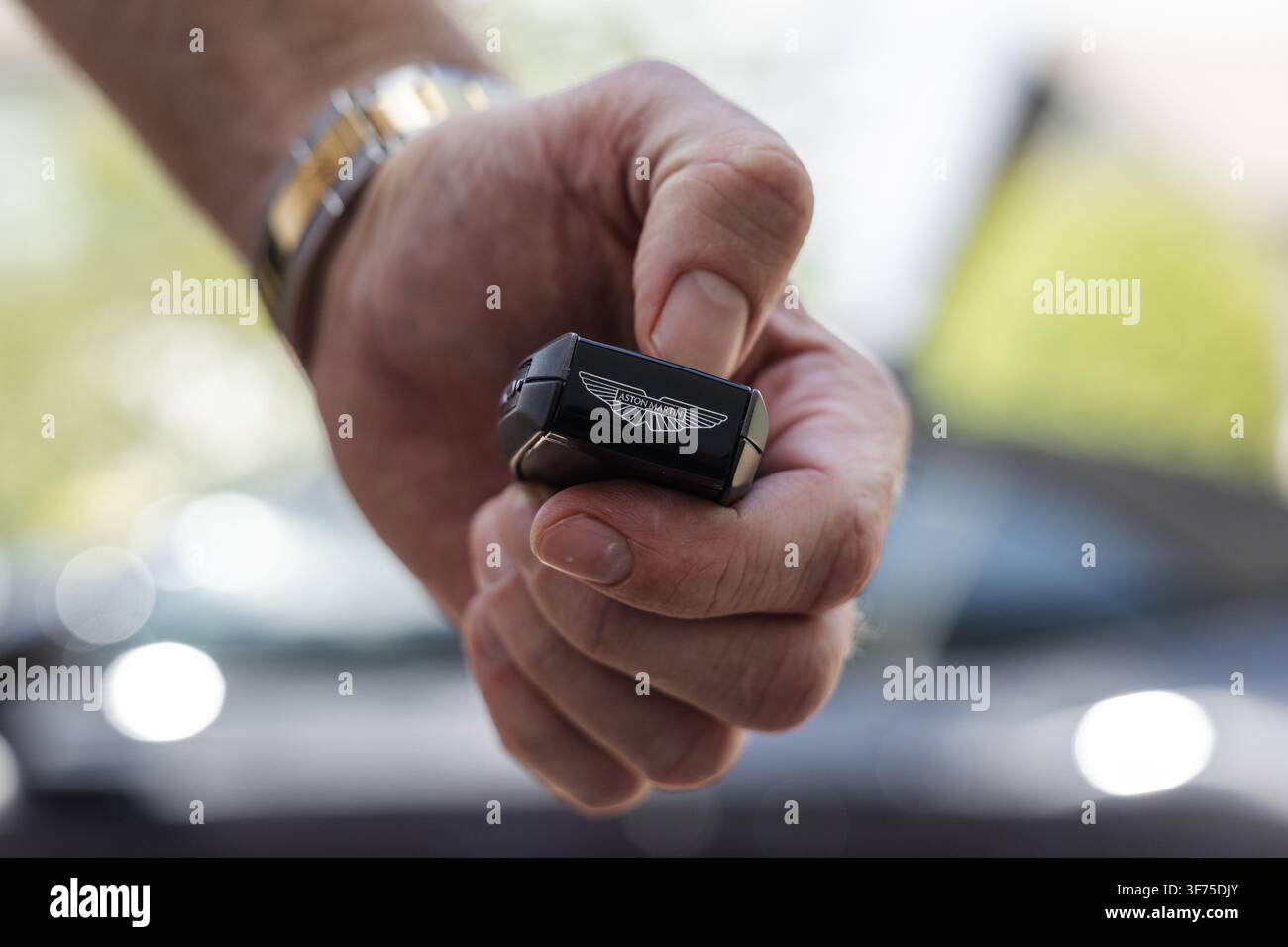 Ljubljana, Slowenien - 25. Juni 2026: Eine Person hält einen Aston Martin-Schlüsselanhänger in einer Autohandelsumgebung. Dies zeigt einen Teil des Autokaufprozesses. Stockfoto