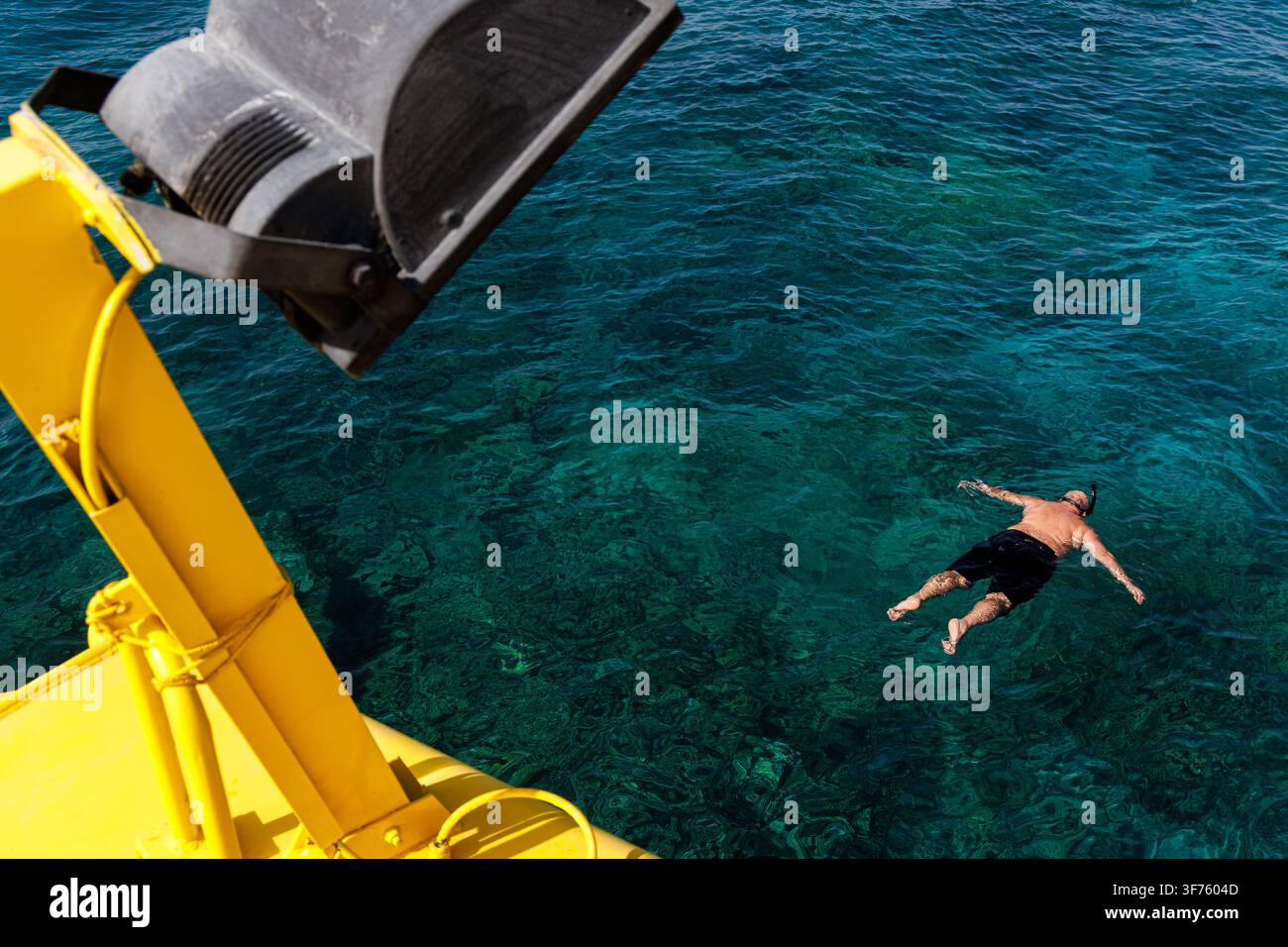 Ein Schnorcher schwebt mit dem Gesicht nach unten auf klarem türkisfarbenem Wasser im Roten Meer in der Nähe von Hurghada, Ägypten, von oben vom Deck eines Bootes aus gesehen. Stockfoto